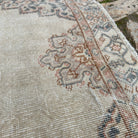 Close-up of the beige vintage Turkish persian style rug showing medallion details, hand-knotted weave, wool and cotton and low pile.