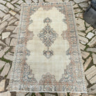 Beige 4' x 6' vintage Turkish persian style rug in wool and cotton, shown on the floor.