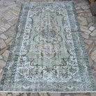Green 5' x 8' vintage Turkish persian style rug in wool and cotton, shown on the floor.