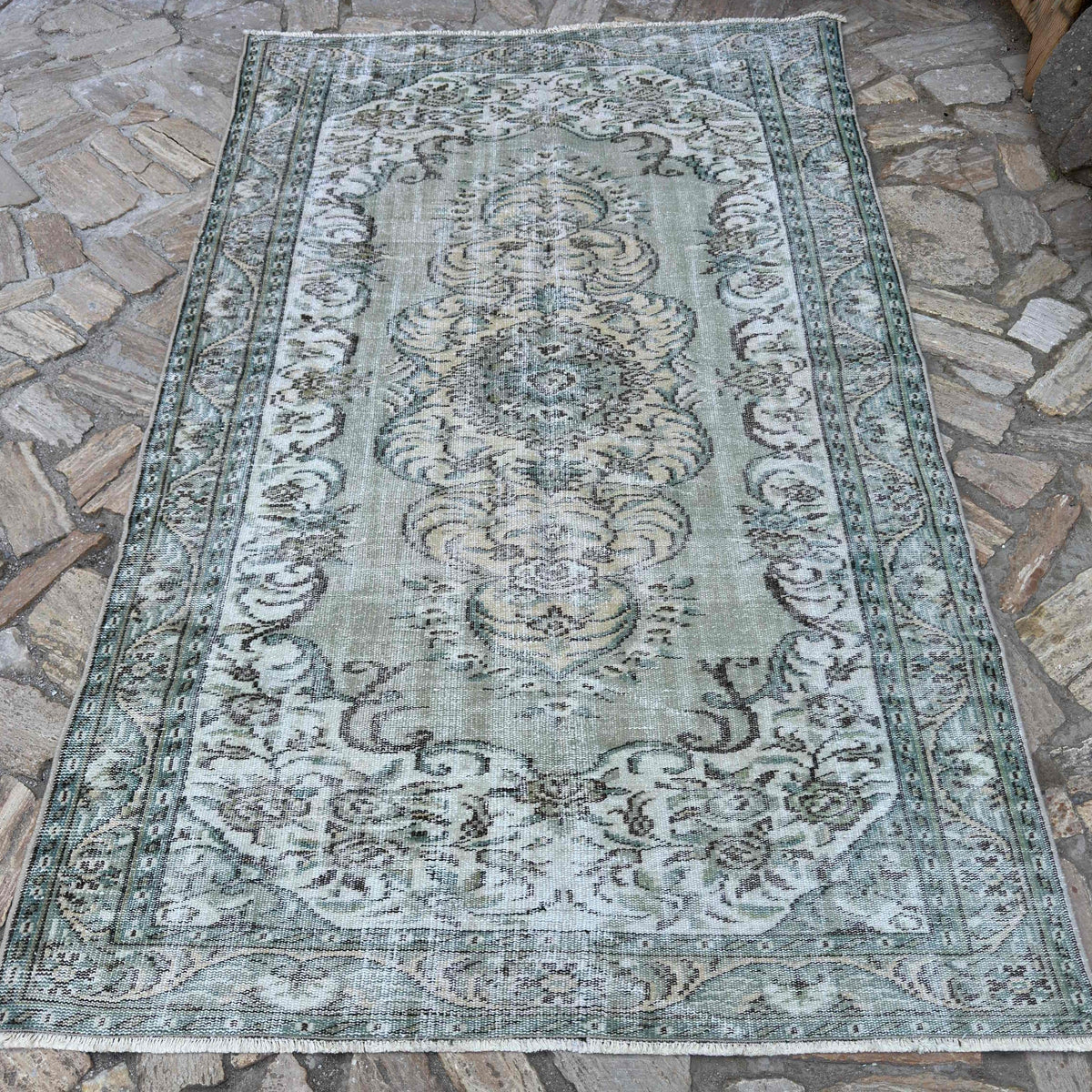 Green 5' x 8' vintage Turkish persian style rug in wool and cotton, shown on the floor.