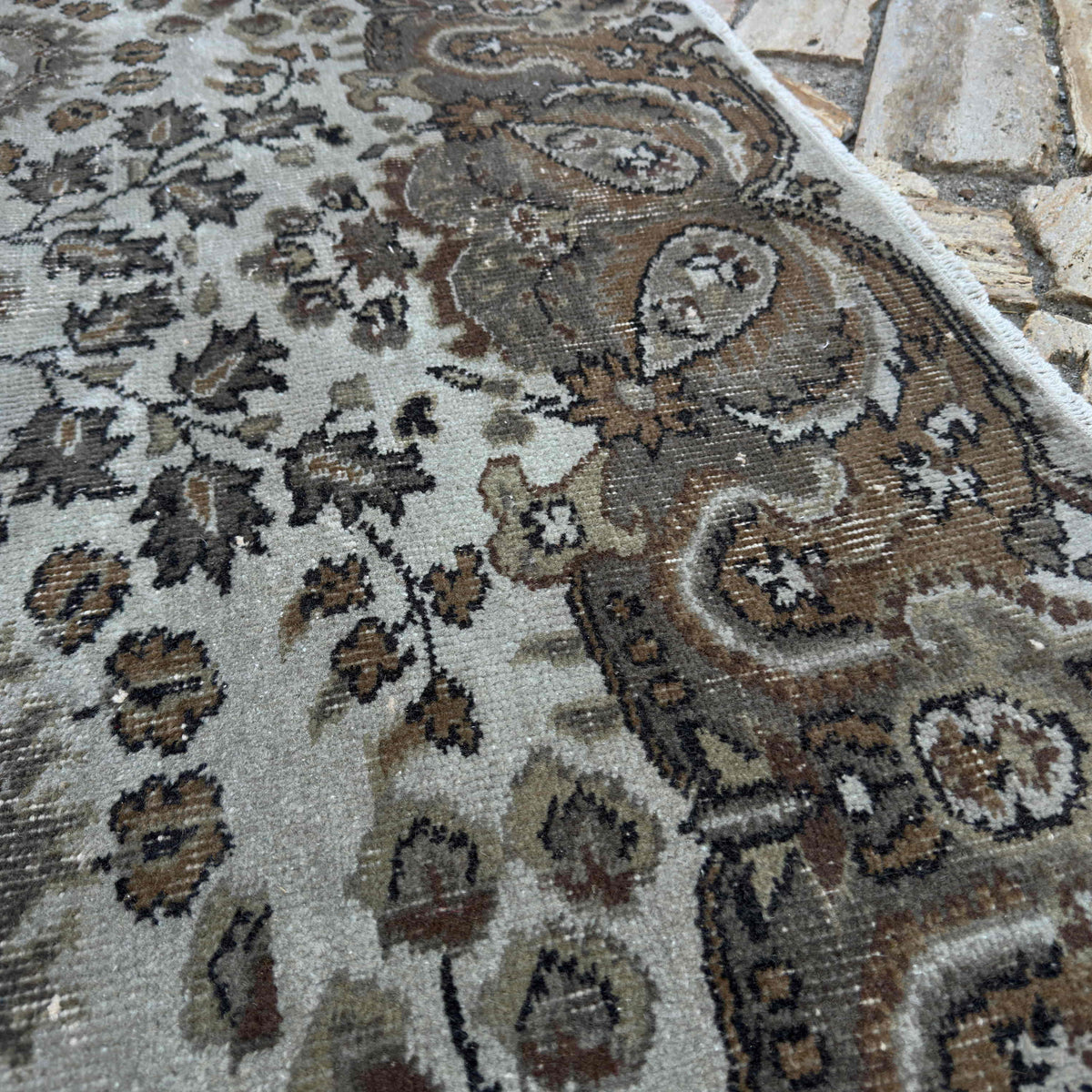 Close-up of the brown vintage Turkish persian style rug showing geometric details, hand-knotted weave, wool and cotton and low pile.