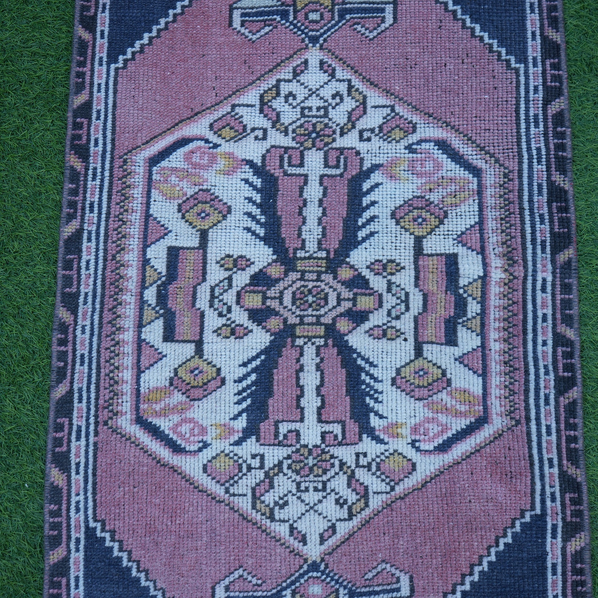 Close-up of the pink vintage Turkish rug showing traditional details, hand-knotted weave, wool and cotton and low pile.