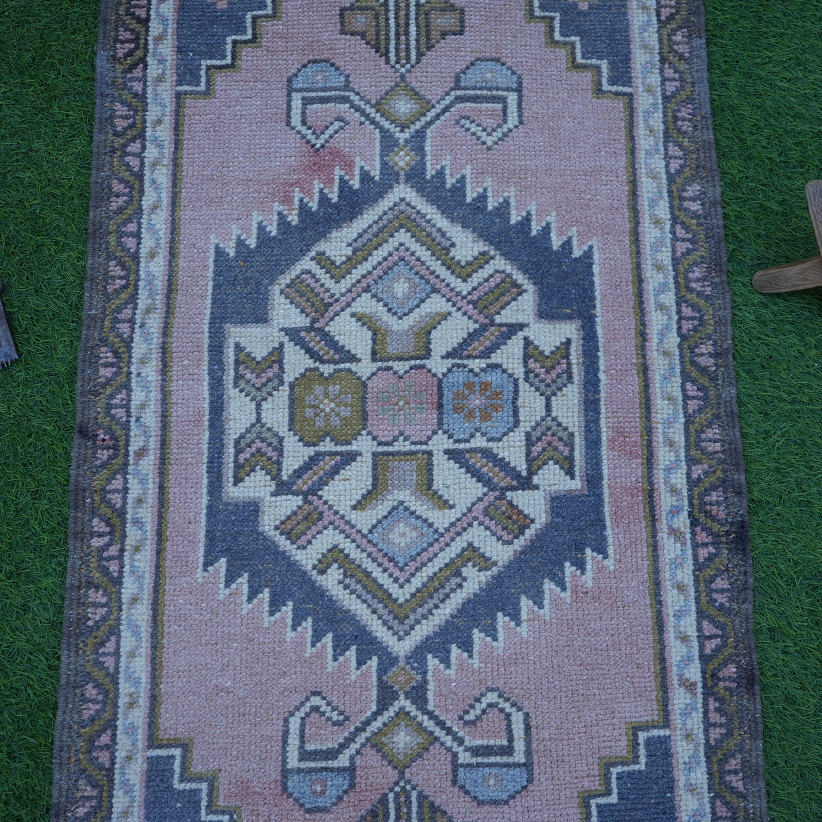 Close-up of the pink vintage Turkish rug showing traditional details, hand-knotted weave, wool and cotton and low pile.