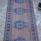Close-up of the pink vintage Turkish runner rug showing traditional details, hand-knotted weave, wool and cotton and low pile.