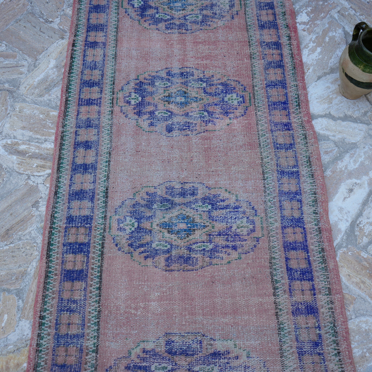 Close-up of the pink vintage Turkish runner rug showing traditional details, hand-knotted weave, wool and cotton and low pile.