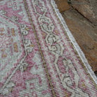 Close-up of the pale pink vintage Turkish runner rug showing neutral details, hand-knotted weave, wool and cotton and low pile.