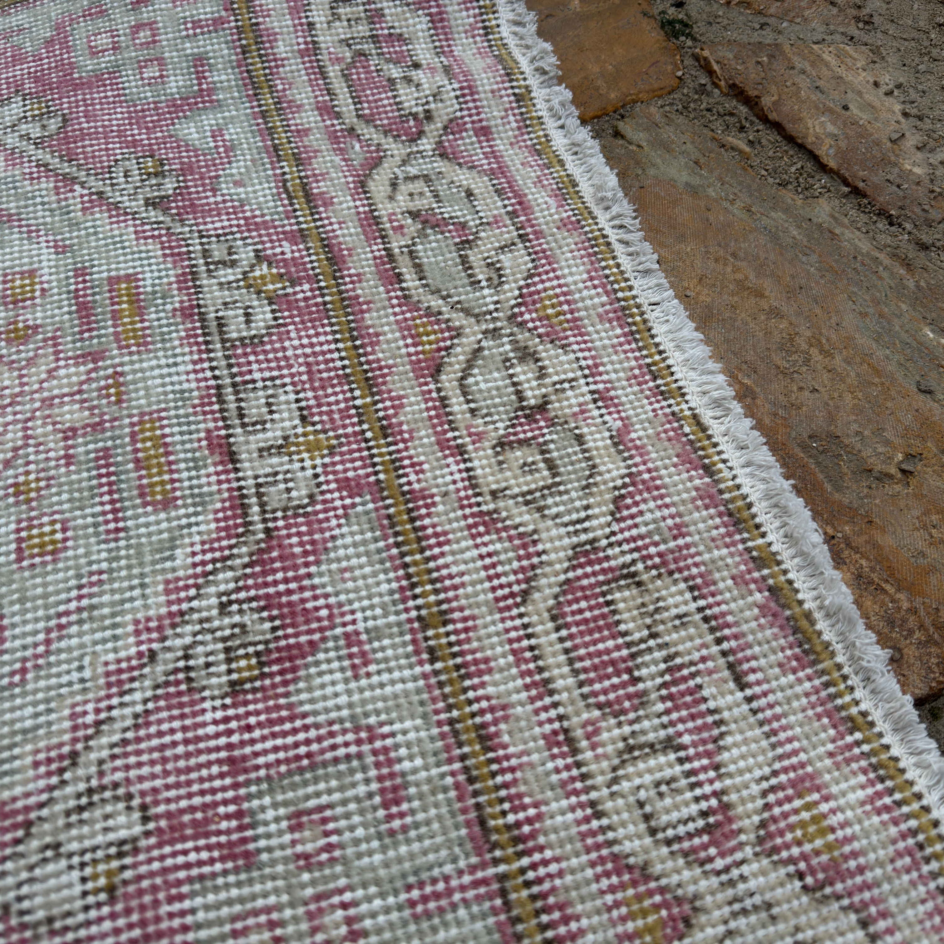 Close-up of the pale pink vintage Turkish runner rug showing neutral details, hand-knotted weave, wool and cotton and low pile.