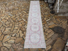 Pale Pink 3' x 14' vintage Turkish runner rug in wool and cotton, shown on the floor.