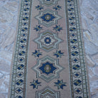 Close-up of the pale pink vintage Turkish runner rug showing traditional details, hand-knotted weave, wool and low pile.