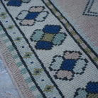 Pale Pink 3' x 14' vintage Turkish runner rug in wool, shown on the floor.