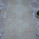 Close-up of the pink vintage Turkish runner rug showing traditional details, hand-knotted weave, wool and cotton and low pile.
