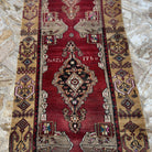 Red 3' x 9' vintage Turkish runner rug in wool and cotton, shown on the floor.