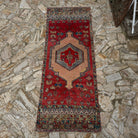 Red 4' x 10' vintage Turkish runner rug in wool, shown on the floor.