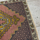 Close-up of the pink vintage Turkish small carpet showing traditional details, hand-knotted weave, wool and cotton and low pile.