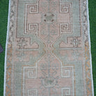 Close-up of the pink vintage Turkish small rug showing neutral details, hand-knotted weave, wool and cotton and low pile.