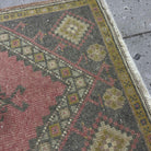 Close-up of the pink vintage Turkish small rug showing traditional details, hand-knotted weave, wool and cotton and low pile.