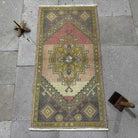 Pink 2' x 3' vintage Turkish small rug in wool and cotton, shown on the floor.