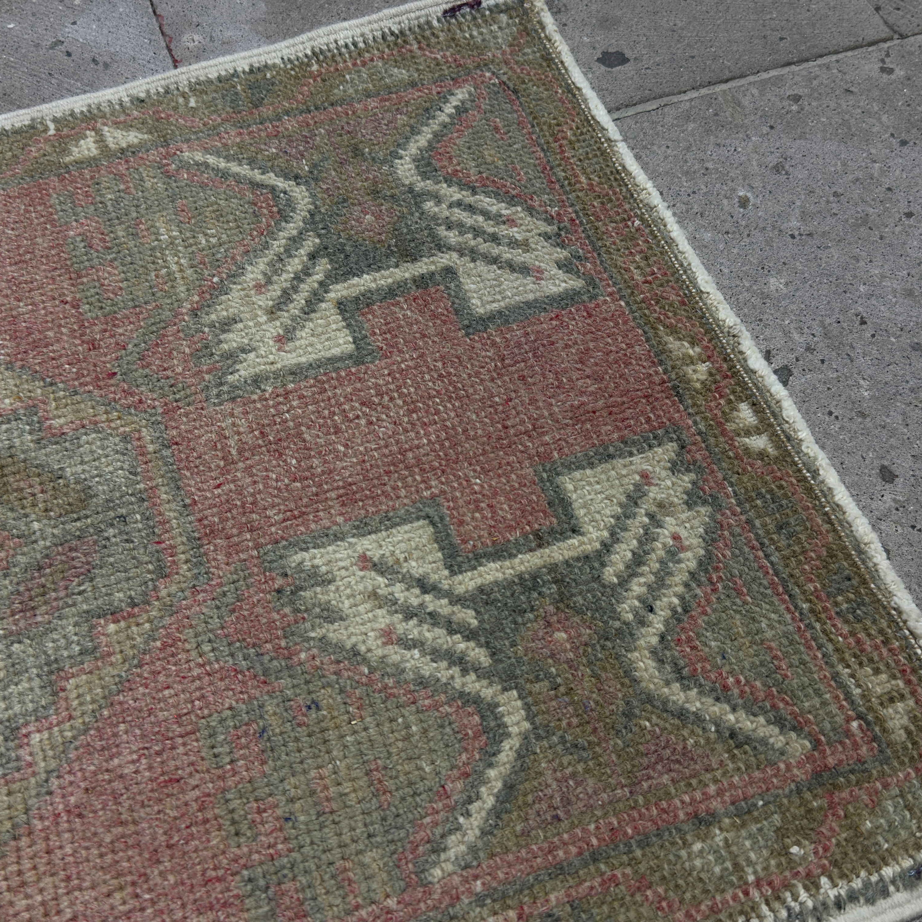 Close-up of the red vintage Turkish small rug showing traditional details, hand-knotted weave, wool and cotton and low pile.