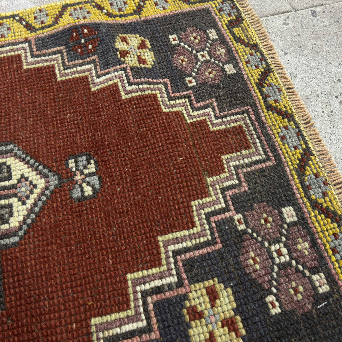 Close-up of the red vintage Turkish small rug showing traditional details, hand-knotted weave, wool and cotton and low pile.