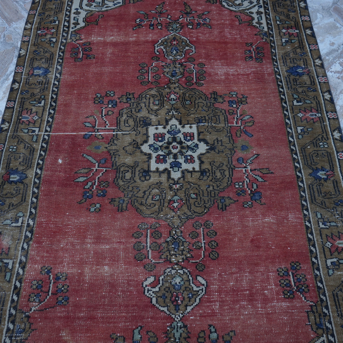 Close-up of the red vintage Turkish tradiitonal rug showing traditional details, hand-knotted weave, wool and cotton and low pile.