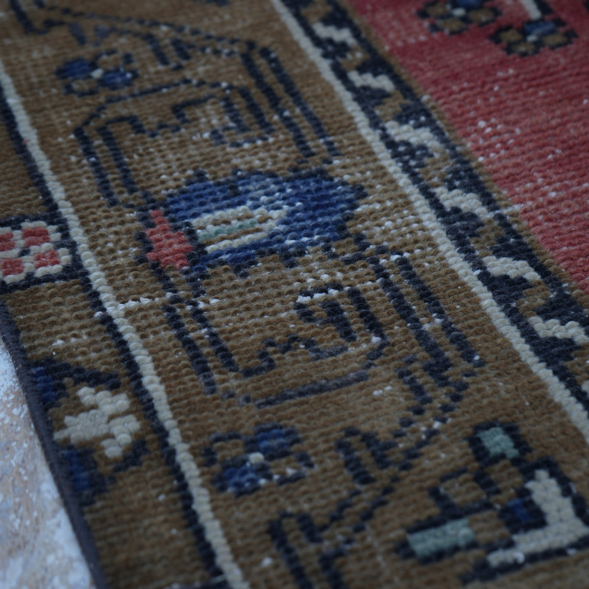 Red 5' x 9' vintage Turkish tradiitonal rug in wool and cotton, shown on the floor.