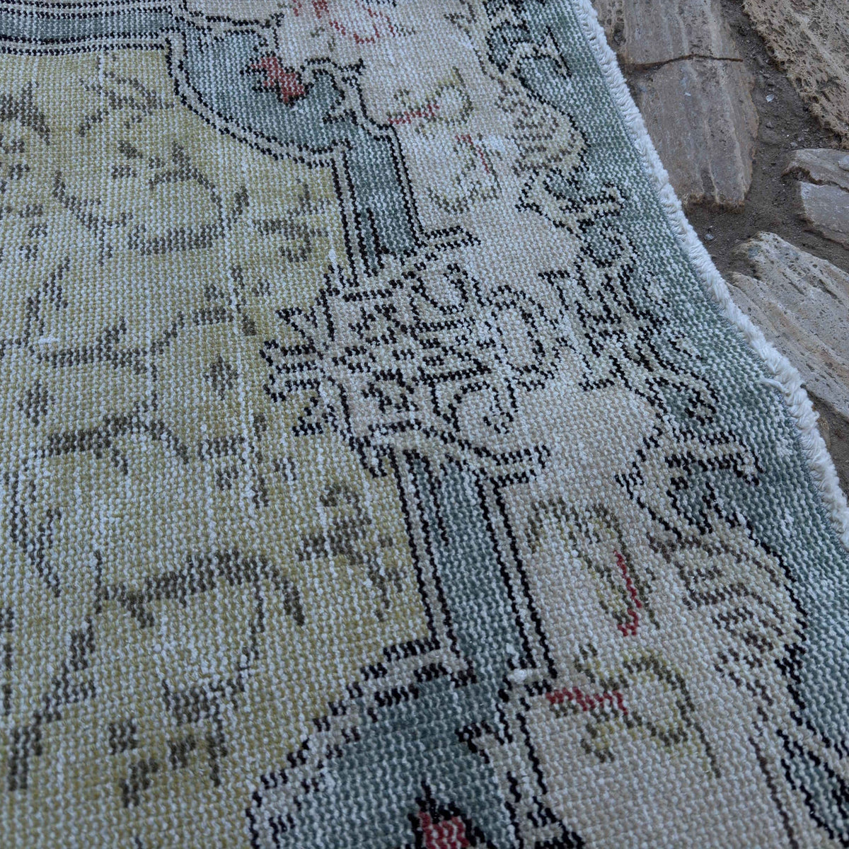 Close-up of the pale green vintage Turkish traditional rug showing traditional details, hand-knotted weave, wool and cotton and low pile.