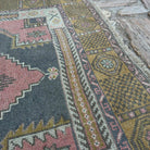 Close-up of the pale red vintage Turkish traditional rug showing traditional details, hand-knotted weave, wool and cotton and low pile.