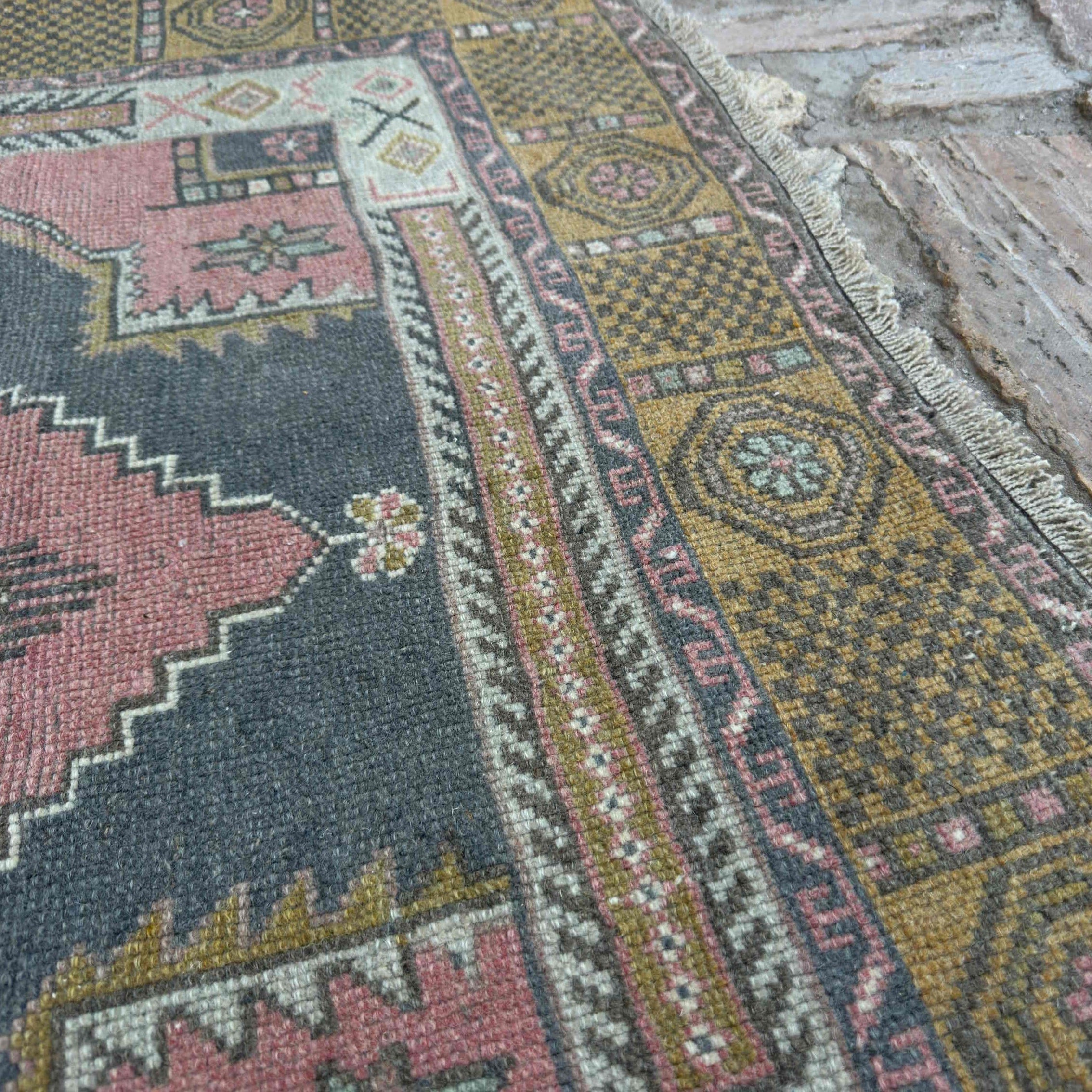 Close-up of the pale red vintage Turkish traditional rug showing traditional details, hand-knotted weave, wool and cotton and low pile.