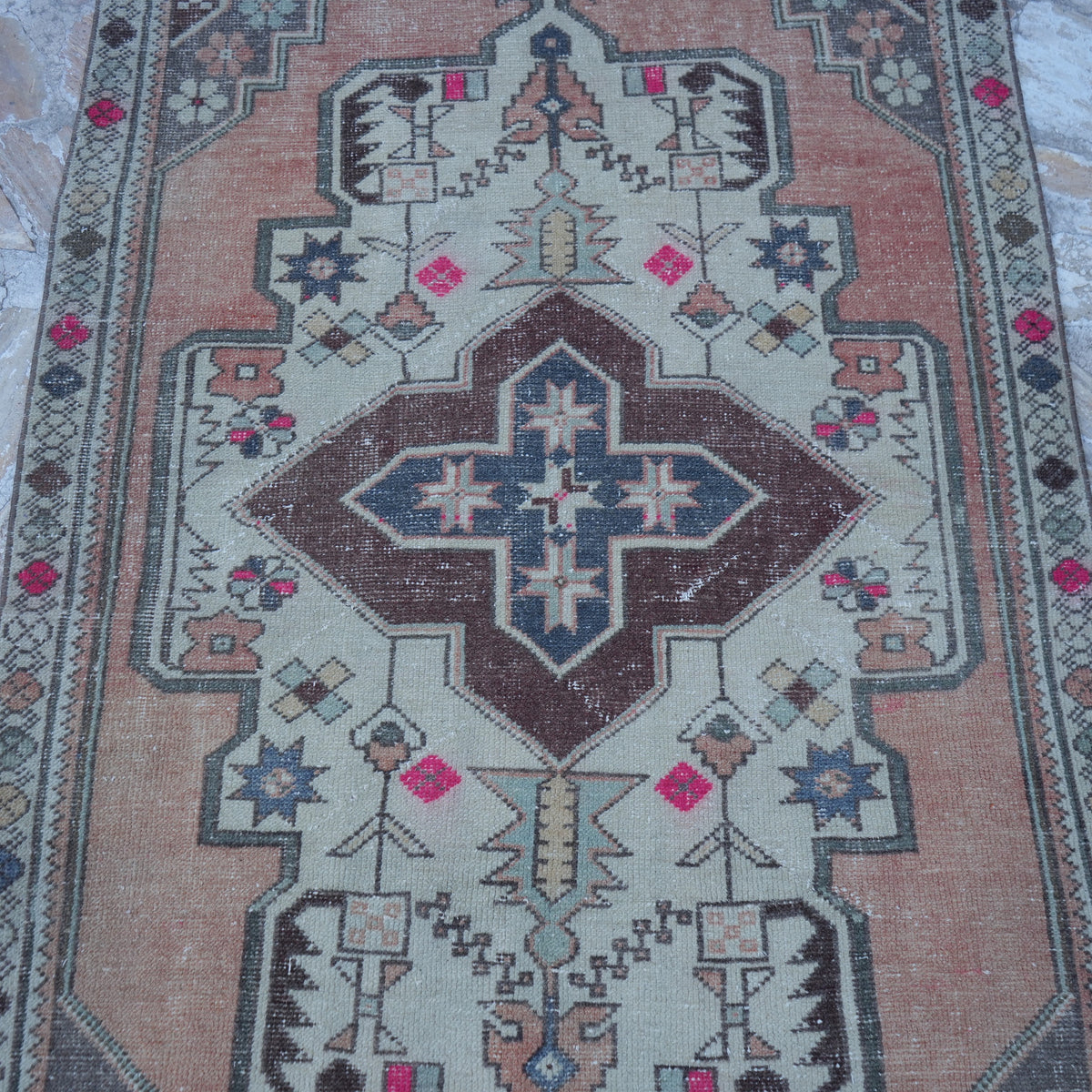 Close-up of the orange vintage Turkish traditional rug showing traditional details, hand-knotted weave, wool and cotton and low pile.