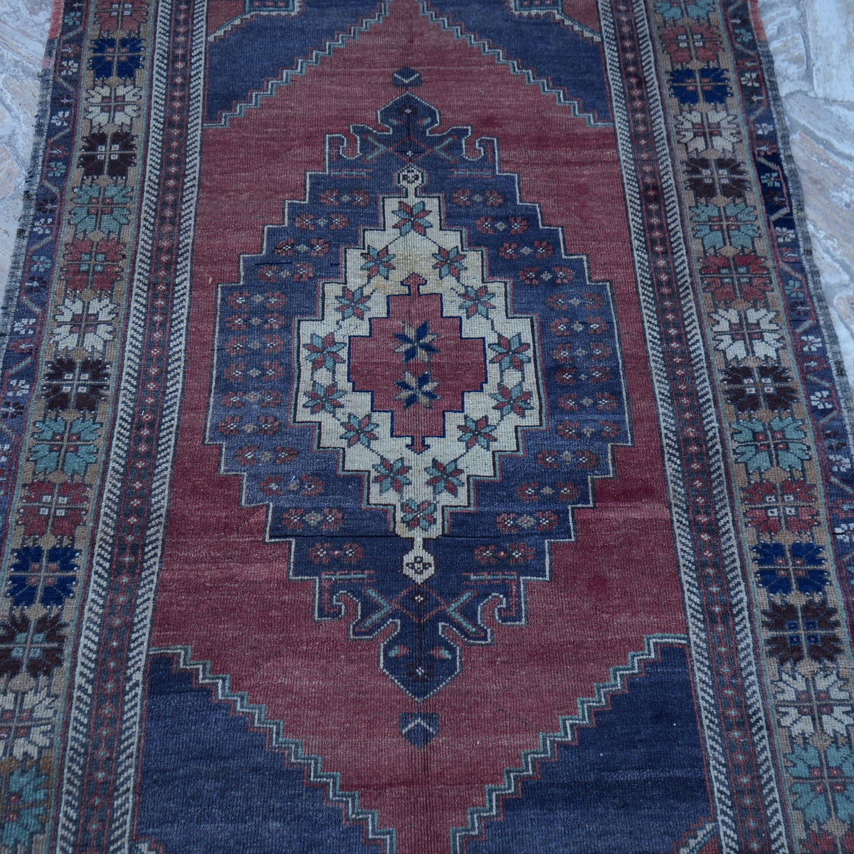 Close-up of the red vintage Turkish traditional rug showing medallion details, hand-knotted weave, wool and low pile.