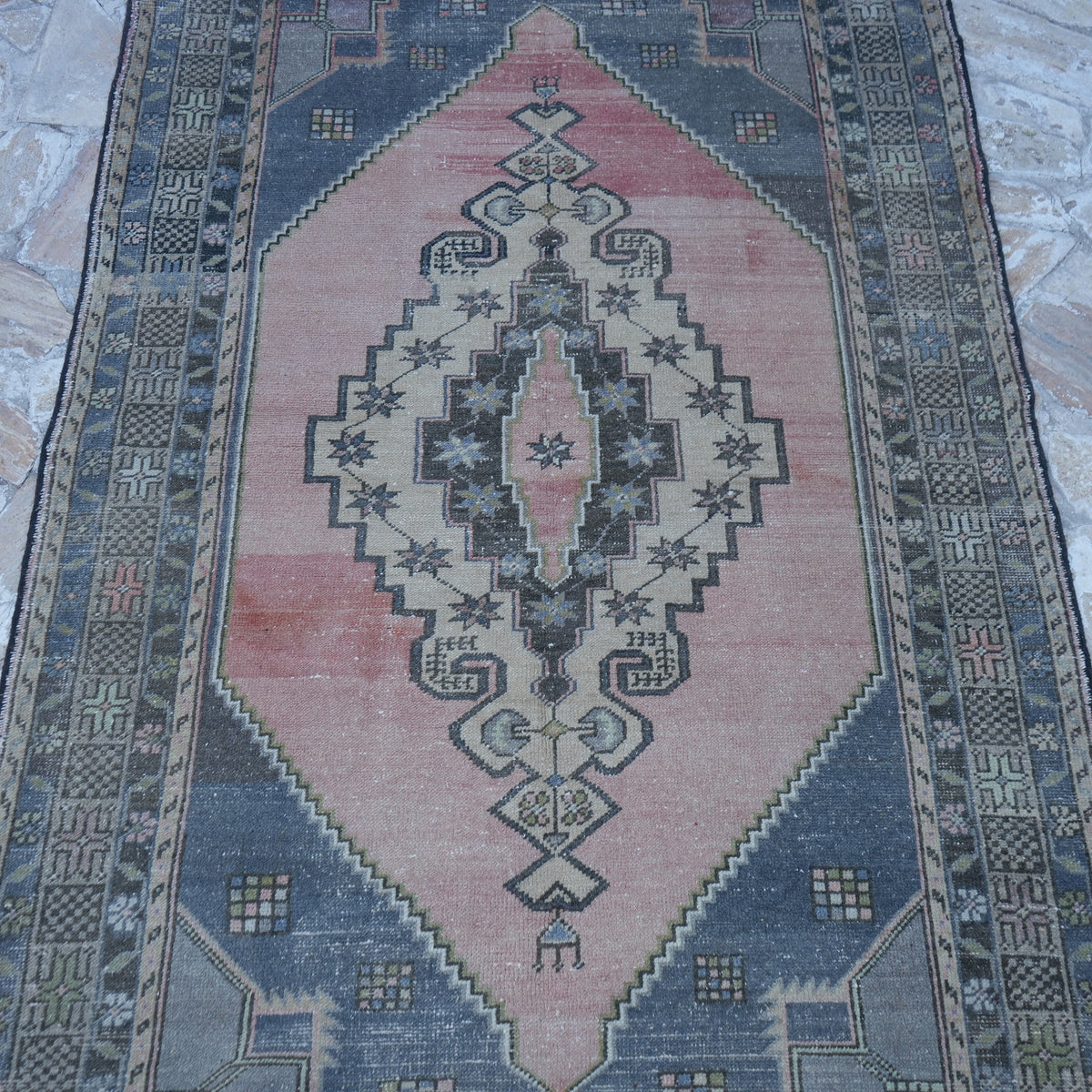 Close-up of the pink vintage Turkish traditional rug showing traditional details, hand-knotted weave, wool and cotton and low pile.