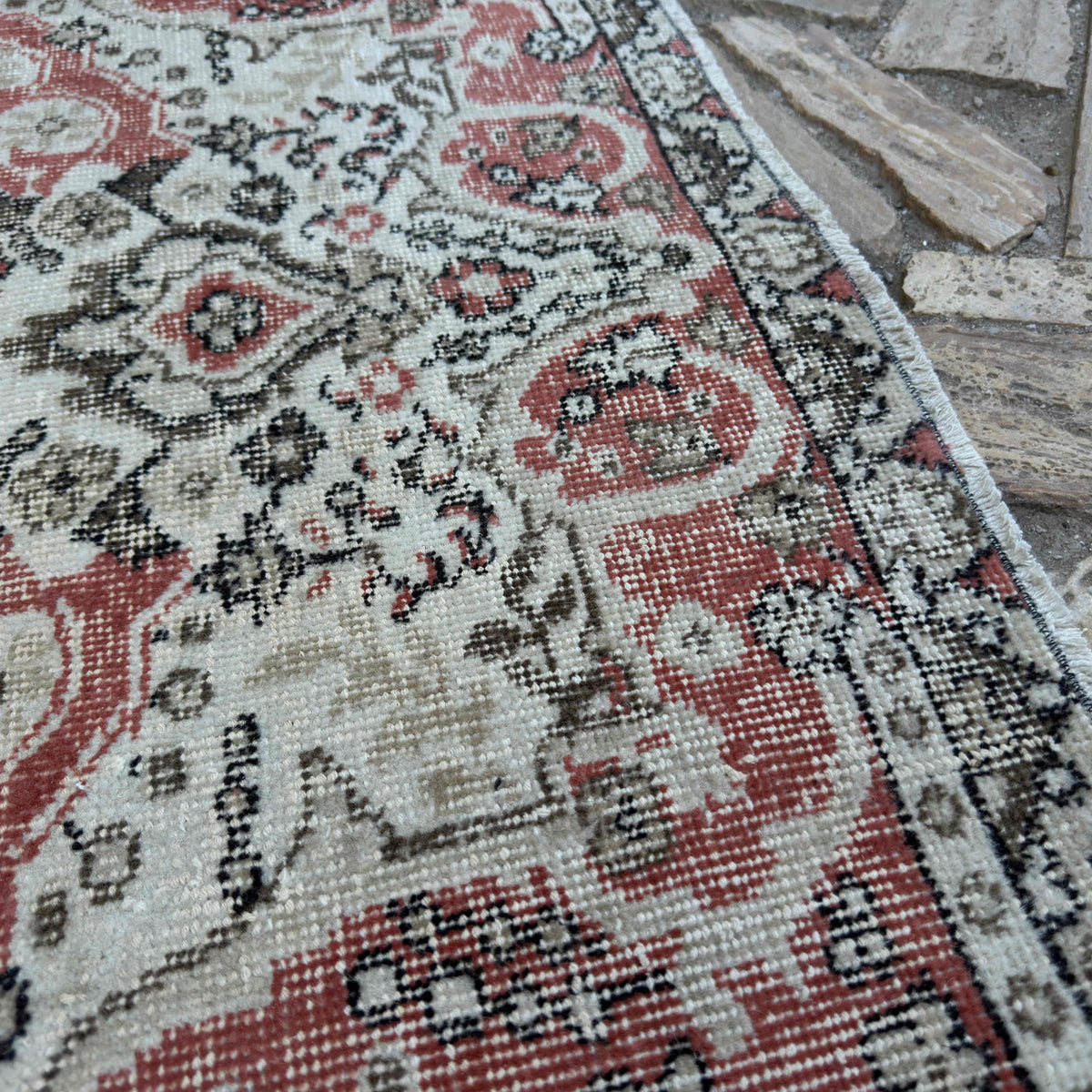 Close-up of the pale red vintage Turkish traditional rug showing medallion details, hand-knotted weave, wool and cotton and low pile.