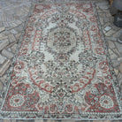 Pale Red 5' x 9' vintage Turkish traditional rug in wool and cotton, shown on the floor.