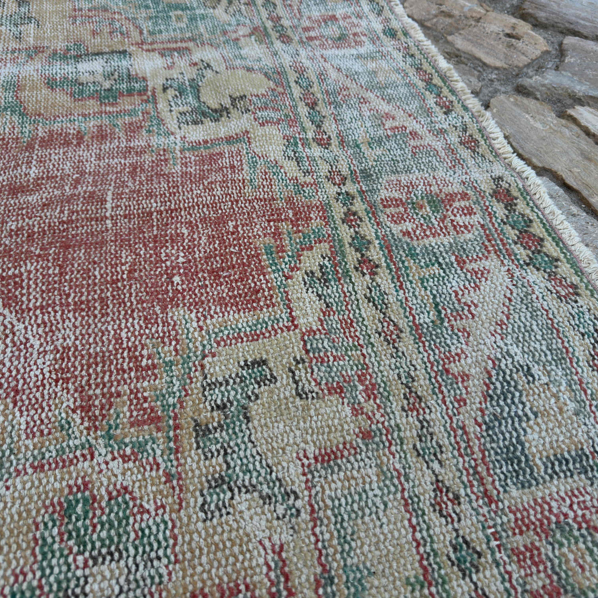 Close-up of the pink vintage Turkish traditional rug showing medallion details, hand-knotted weave, wool and cotton and low pile.