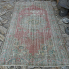 Pink 5' x 9' vintage Turkish traditional rug in wool and cotton, shown on the floor.