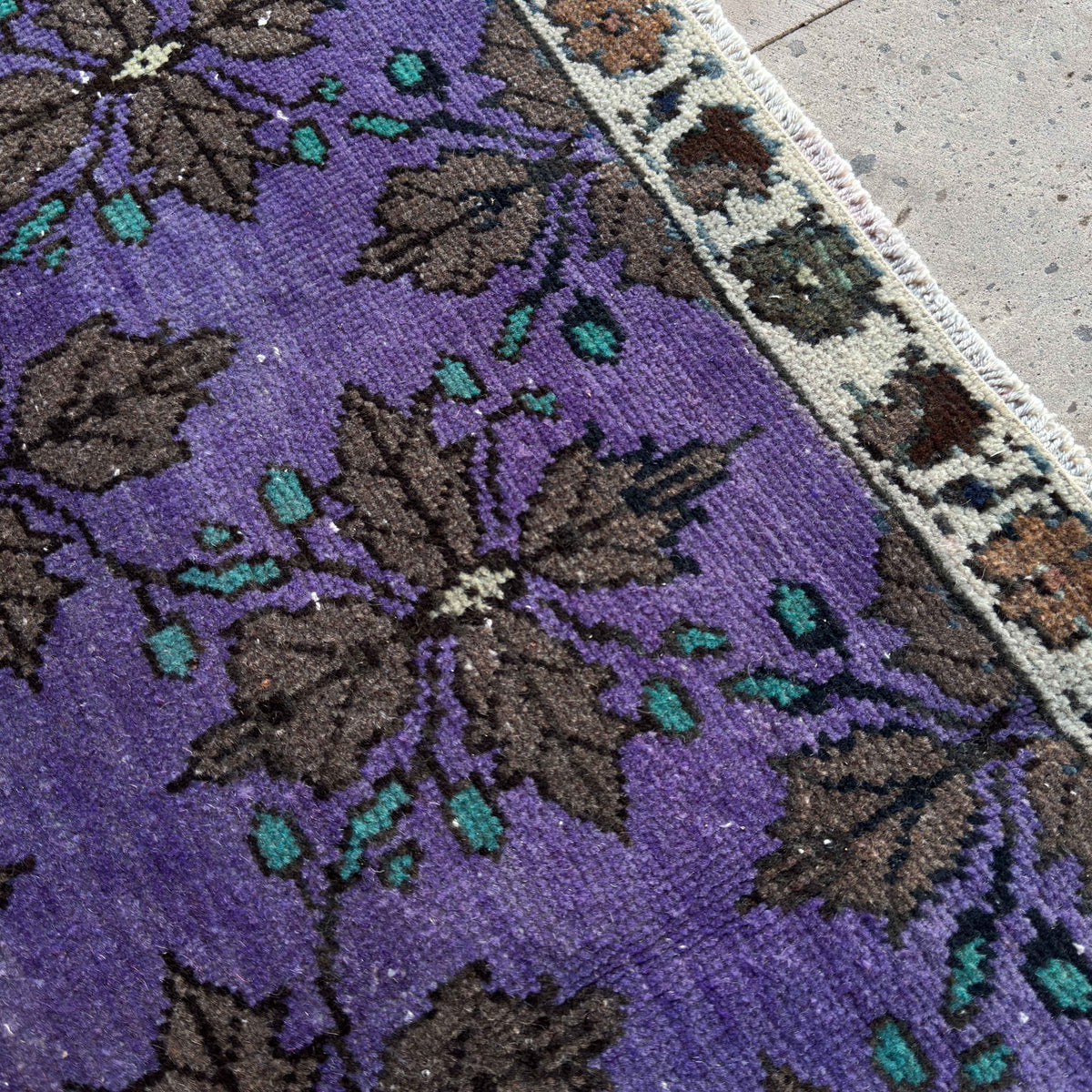 Close-up of the purple vintage Turkish traditional rug showing floral details, hand-knotted weave, wool and cotton and low pile.