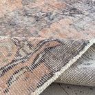 Close-up of the pink vintage Turkish traditional rug showing traditional details, hand-knotted weave, wool and cotton and low pile.