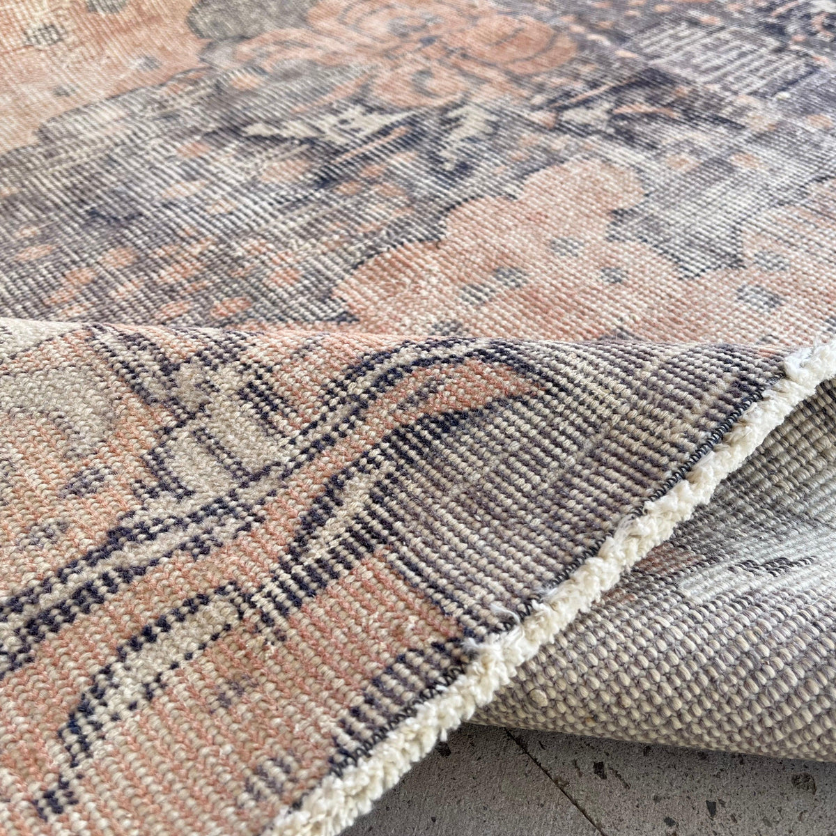 Close-up of the pink vintage Turkish traditional rug showing traditional details, hand-knotted weave, wool and cotton and low pile.