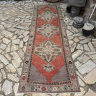 Red 3' x 11' vintage Turkish traditional runner rug in wool and cotton, shown on the floor.