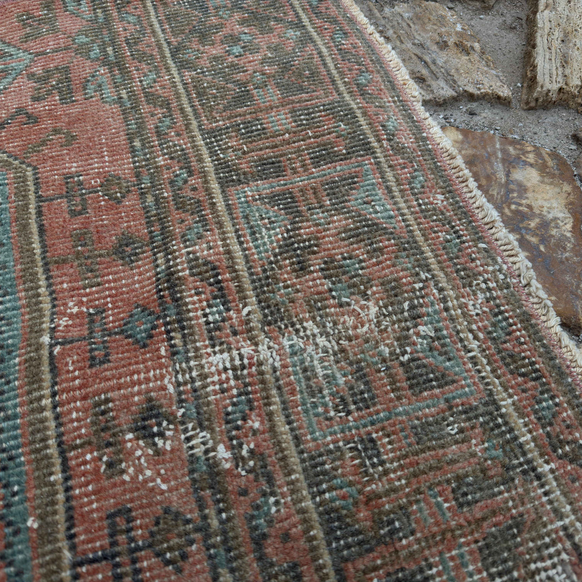 Close-up of the pale red vintage Turkish traditional runner rug showing traditional details, hand-knotted weave, wool and cotton and low pile.