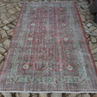 Red 5' x 8' vintage Turkish traditonal rug in wool and cotton, shown on the floor.