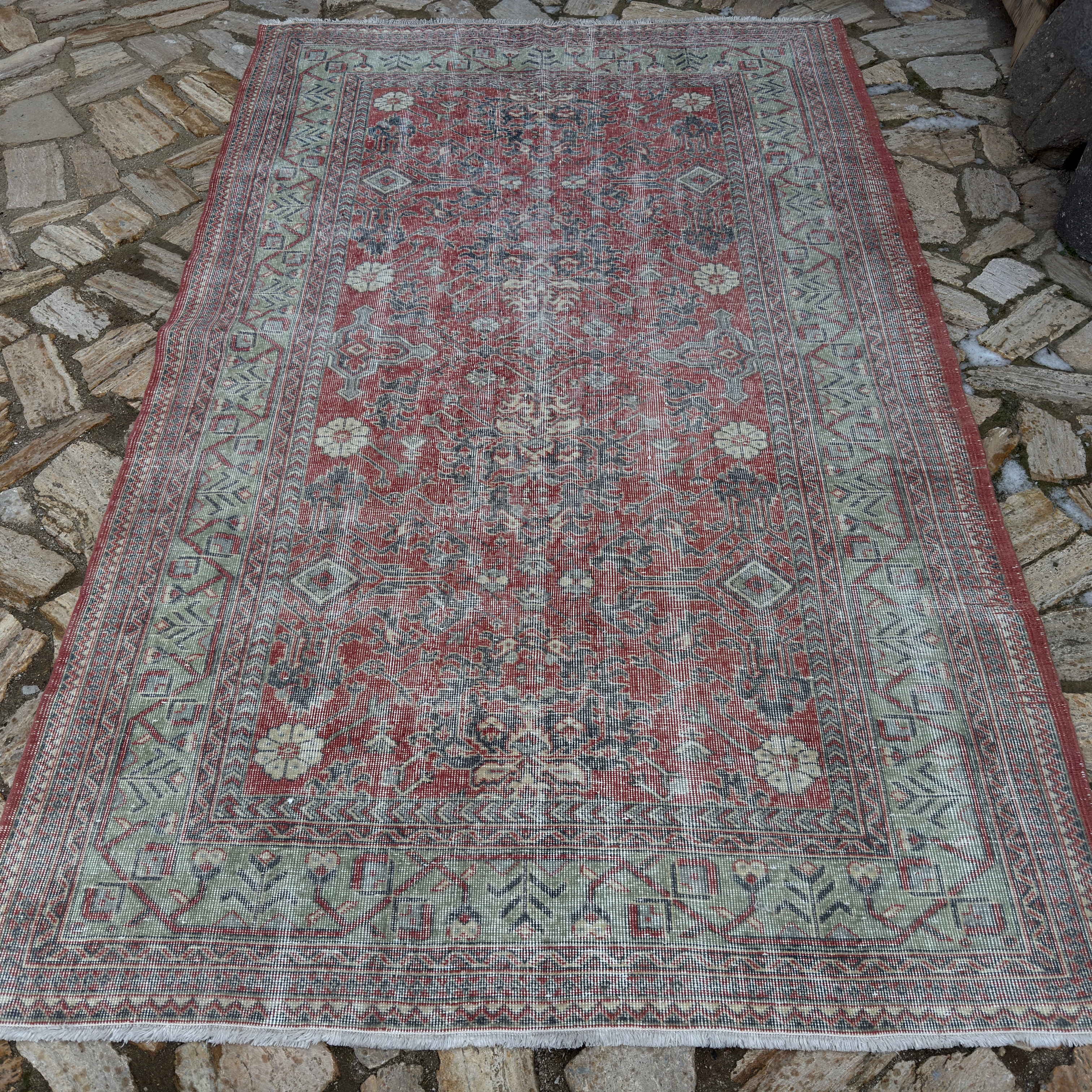 Red 5' x 8' vintage Turkish traditonal rug in wool and cotton, shown on the floor.