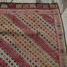 Close-up of the brown vintage Turkish tribal kilim rug showing geometric details, flatweave construction, wool and cotton and low pile.