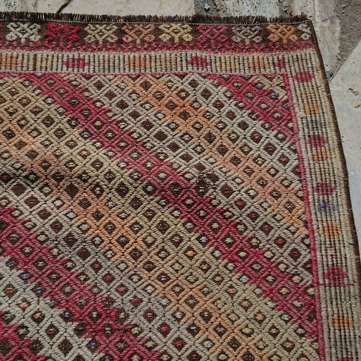 Close-up of the brown vintage Turkish tribal kilim rug showing geometric details, flatweave construction, wool and cotton and low pile.