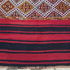 Close-up of the red vintage Turkish tribal kilim rug showing striped details, flatweave construction, wool and cotton and low pile.