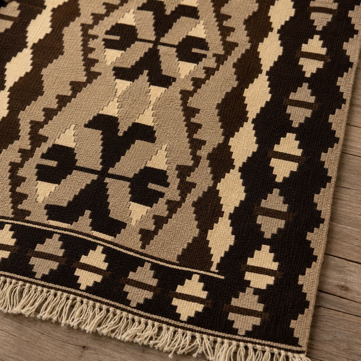 Macro detail of a brown and cream hand-woven Turkish kilim, Isaias, showing flatweave texture and fringe edge
