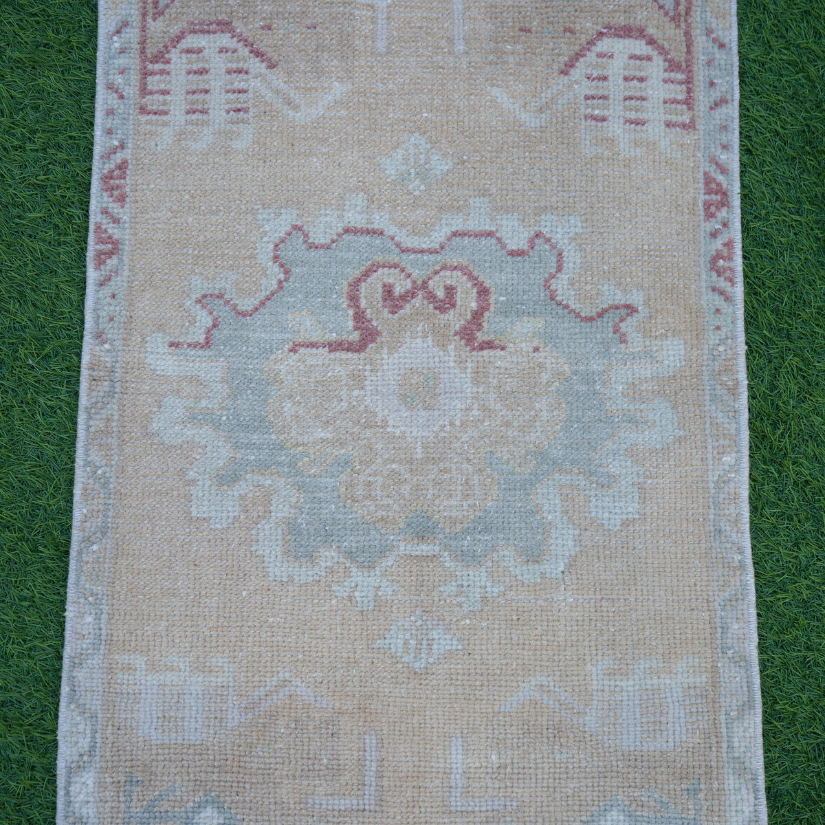Close-up of the beige vintage turkish rug showing traditional details, hand-knotted weave, wool and cotton and low pile.