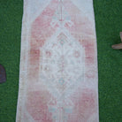 Close-up of the pale red vintage turkish rug showing neutral details, hand-knotted weave, wool and cotton and low pile.