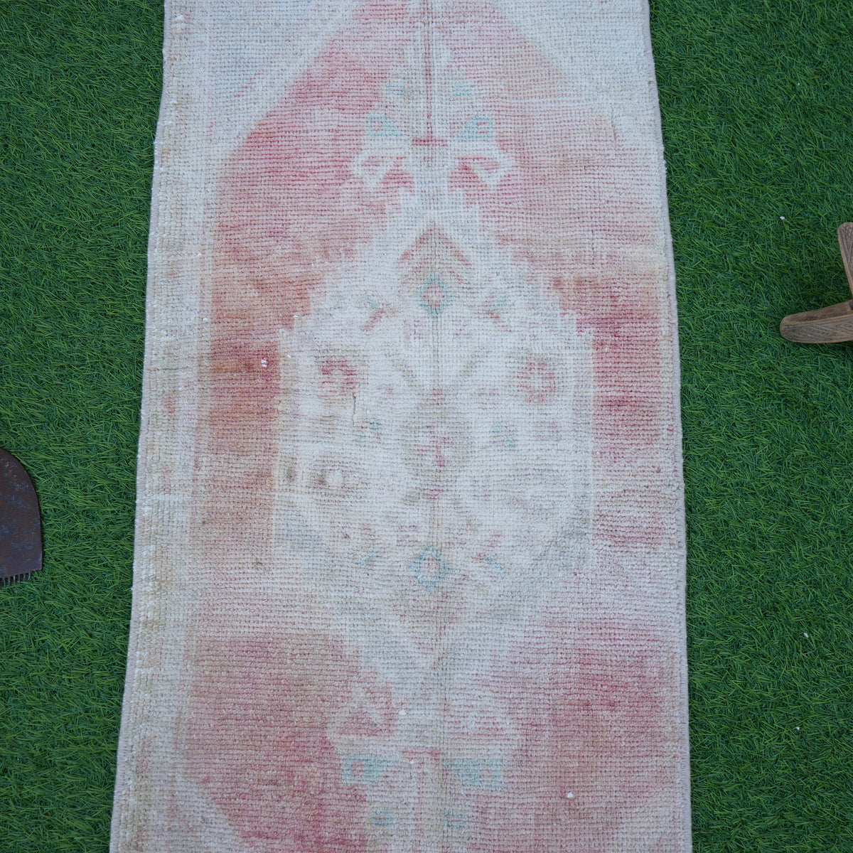 Close-up of the pale red vintage turkish rug showing neutral details, hand-knotted weave, wool and cotton and low pile.