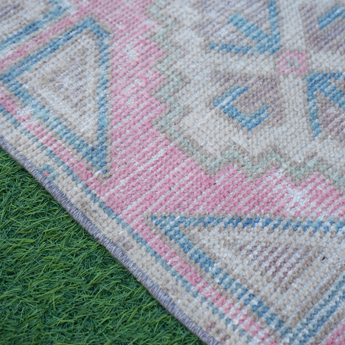 Pink 1' x 3' vintage turkish rug in wool and cotton, shown on the floor.